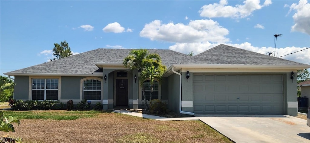 single story home with stucco siding, concrete driveway, an attached garage, a shingled roof, and a front yard