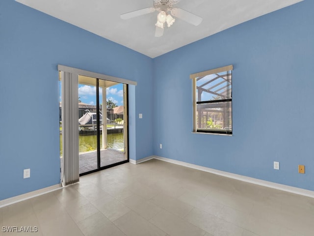 empty room featuring a ceiling fan, baseboards, and a water view