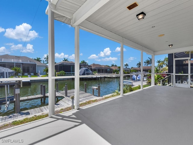 unfurnished sunroom with a water view, a residential view, and a wall of windows