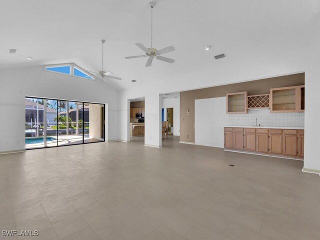 unfurnished living room with a sink, ceiling fan, high vaulted ceiling, baseboards, and light floors