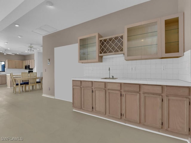 kitchen featuring a sink, ceiling fan, decorative backsplash, stainless steel microwave, and light brown cabinetry