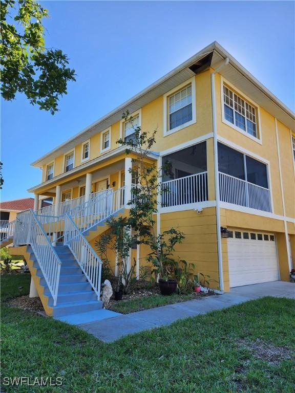 view of front of property with stucco siding, an attached garage, stairway, and a front lawn