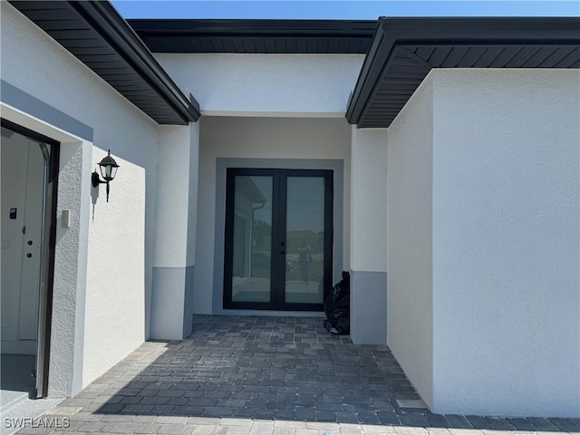 view of exterior entry with stucco siding, french doors, and elevator