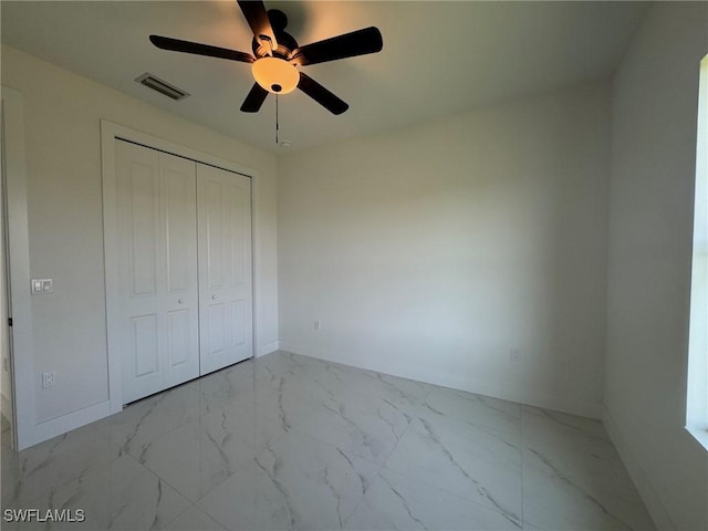 unfurnished bedroom with baseboards, marble finish flooring, a closet, and ceiling fan