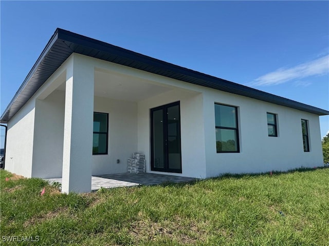 back of property with stucco siding, a yard, and a patio area