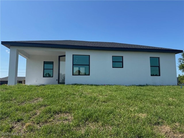 rear view of house featuring stucco siding and a lawn