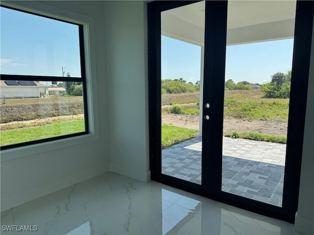 doorway to outside featuring marble finish floors and baseboards