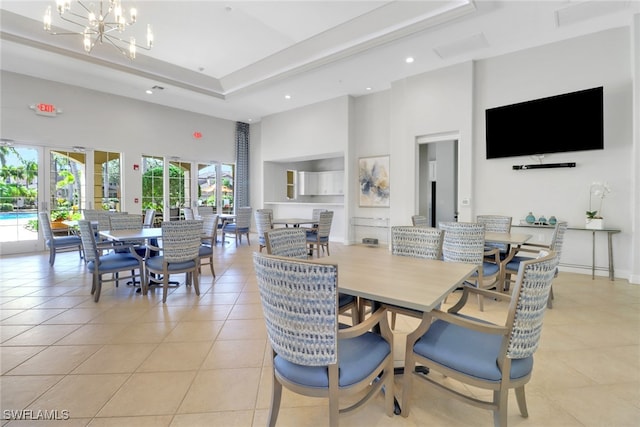 dining room with a towering ceiling, light tile patterned floors, recessed lighting, a chandelier, and a raised ceiling