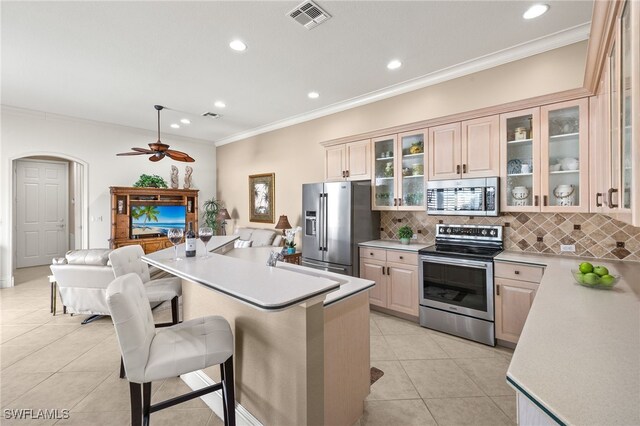 3417 Marbella Ct, Bonita Springs, FL 34134 - kitchen featuring appliances with stainless steel finishes, open floor plan, ornamental molding, light countertops, and backsplash