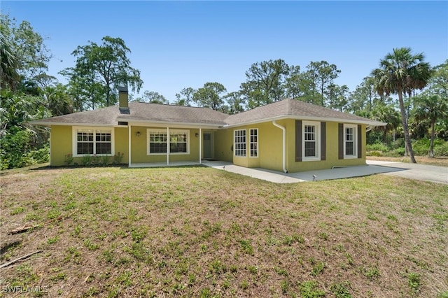 681 23rd St NW, Naples, FL 34120 - ranch-style house with stucco siding, a front yard, a patio area, and a chimney