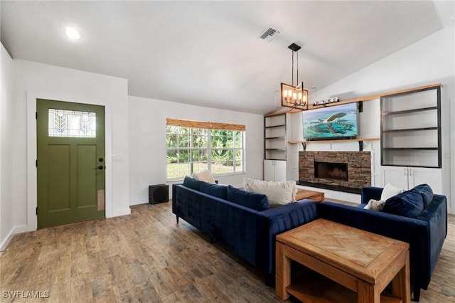 681 23rd St NW, Naples, FL 34120 - living area featuring wood finished floors, vaulted ceiling, a chandelier, a stone fireplace, and baseboards