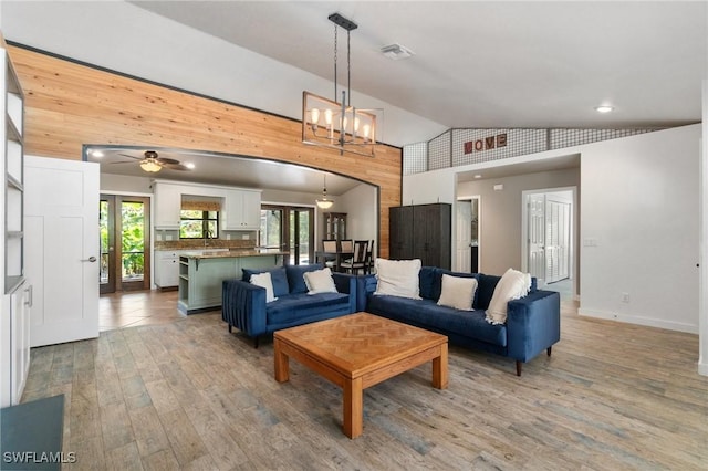 681 23rd St NW, Naples, FL 34120 - living room with vaulted ceiling, wood finished floors, a chandelier, wood walls, and a ceiling fan