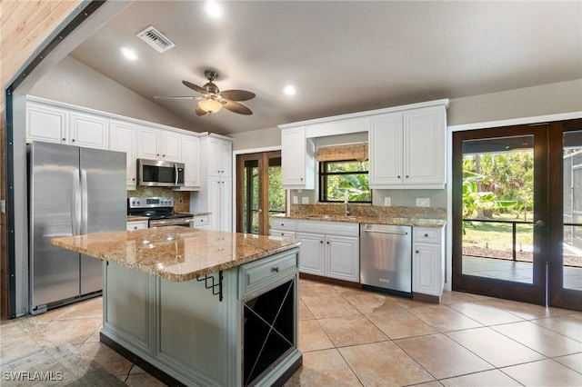 681 23rd St NW, Naples, FL 34120 - kitchen featuring appliances with stainless steel finishes, white cabinetry, decorative backsplash, a ceiling fan, and light stone counters