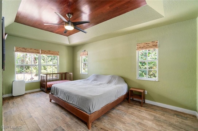 681 23rd St NW, Naples, FL 34120 - bedroom with wood finished floors, baseboards, a tray ceiling, a textured wall, and ceiling fan