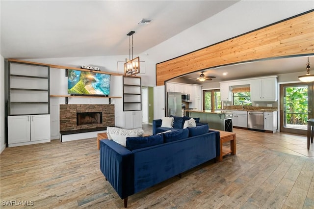 681 23rd St NW, Naples, FL 34120 - living area with lofted ceiling, light wood-style floors, a stone fireplace, wooden walls, and a chandelier