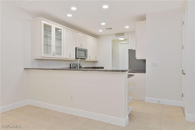 4910 SW 17th Pl Unit 4B, Cape Coral, FL 33914 - kitchen with stainless steel microwave, recessed lighting, refrigerator, white cabinets, and glass insert cabinets