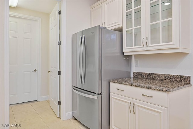 4910 SW 17th Pl Unit 4B, Cape Coral, FL 33914 - kitchen featuring freestanding refrigerator, light tile patterned flooring, glass insert cabinets, dark stone countertops, and white cabinets