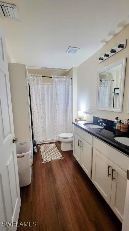 3086 E Briarwood Cir, Labelle, FL 33935 - full bathroom with wood finished floors, toilet, double vanity, a shower with shower curtain, and a tub