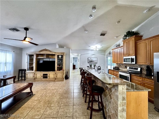 2639 SW 5th St, Cape Coral, FL 33991 - kitchen with appliances with stainless steel finishes, vaulted ceiling, a ceiling fan, a textured ceiling, and a kitchen bar