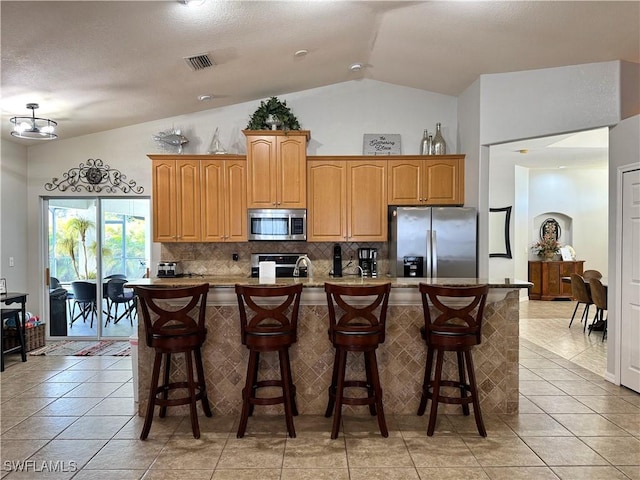 2639 SW 5th St, Cape Coral, FL 33991 - kitchen with appliances with stainless steel finishes, vaulted ceiling, backsplash, an island with sink, and light tile patterned floors
