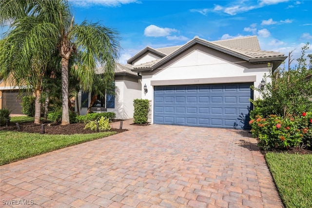single story home featuring stucco siding, decorative driveway, an attached garage, and a tiled roof