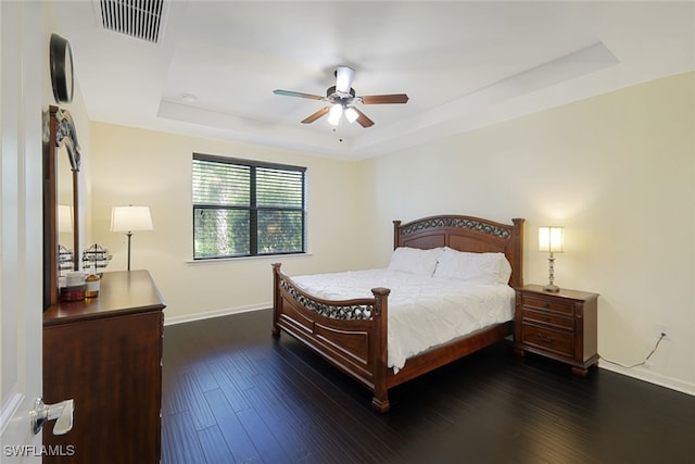bedroom with a tray ceiling, baseboards, dark wood-style floors, and ceiling fan