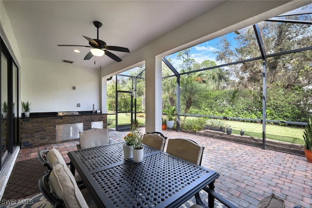 sunroom / solarium with outdoor dining space, a ceiling fan, and exterior kitchen