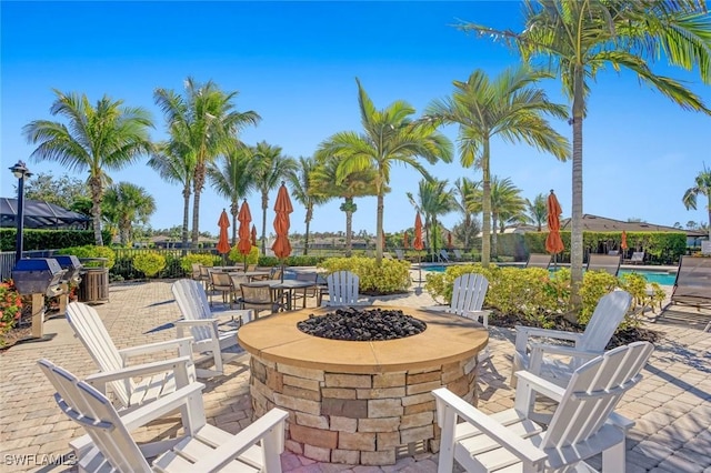 view of patio featuring a fire pit, a grill, and an outdoor pool