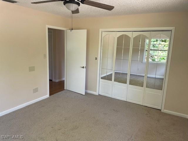 unfurnished bedroom featuring carpet flooring, baseboards, a closet, a textured ceiling, and a ceiling fan
