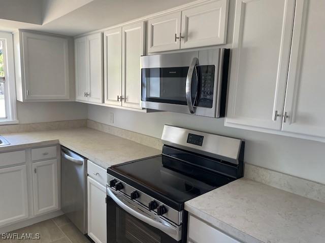 kitchen featuring stainless steel appliances, white cabinetry, and light countertops