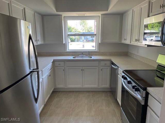 kitchen featuring stainless steel appliances, a sink, and light countertops