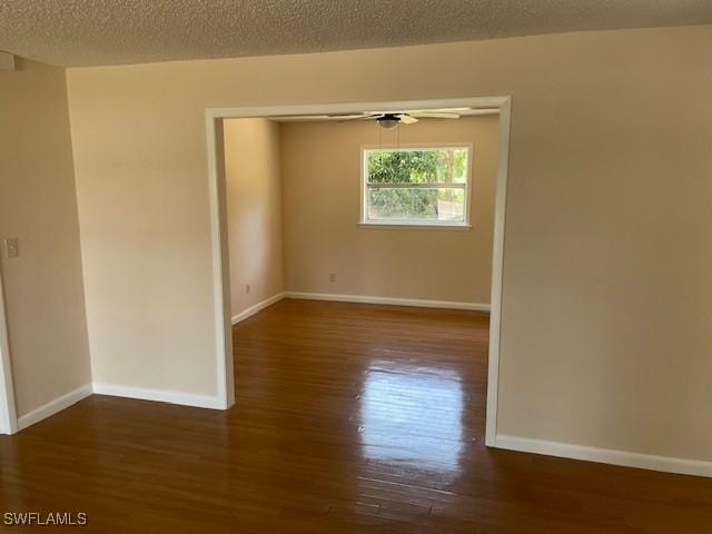 empty room featuring wood finished floors, baseboards, and a textured ceiling