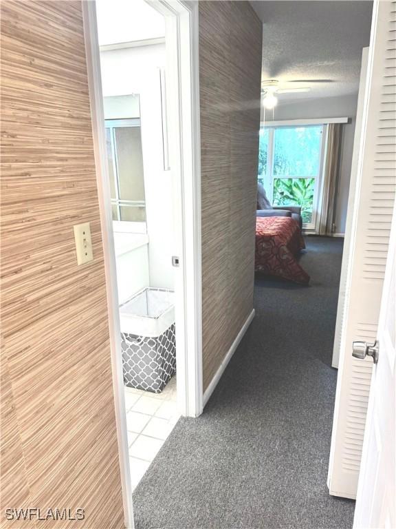 hallway featuring carpet flooring and a textured ceiling