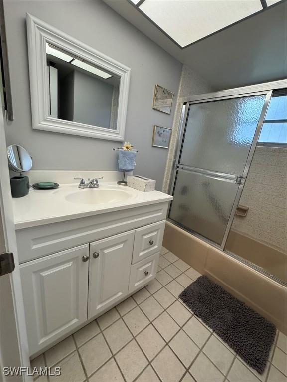 bathroom with tile patterned floors, shower / bath combination with glass door, and vanity