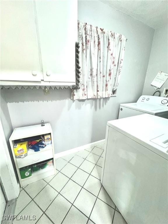 clothes washing area with cabinet space, independent washer and dryer, light tile patterned floors, and baseboards