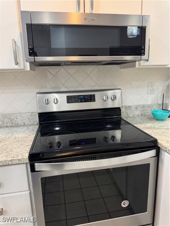kitchen with stainless steel appliances, white cabinetry, tasteful backsplash, and light stone countertops
