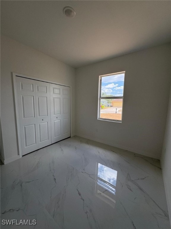 4118 4th St SW, Lehigh Acres, FL 33976 - unfurnished bedroom with light marble finish flooring, a closet, and baseboards