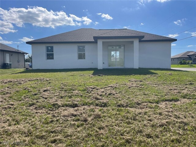 4118 4th St SW, Lehigh Acres, FL 33976 - rear view of house with stucco siding, central AC unit, a yard, and roof with shingles