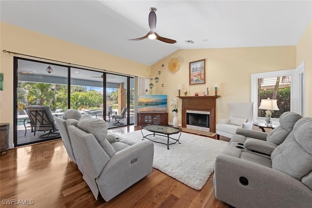 living room with ceiling fan, wood finished floors, lofted ceiling, and a fireplace