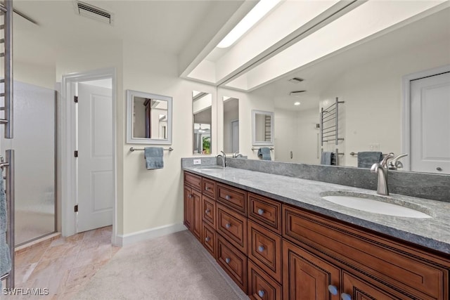 bathroom with baseboards, double vanity, and a shower