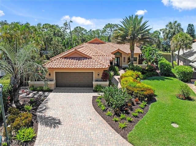 mediterranean / spanish house featuring a garage, a front lawn, stucco siding, and decorative driveway
