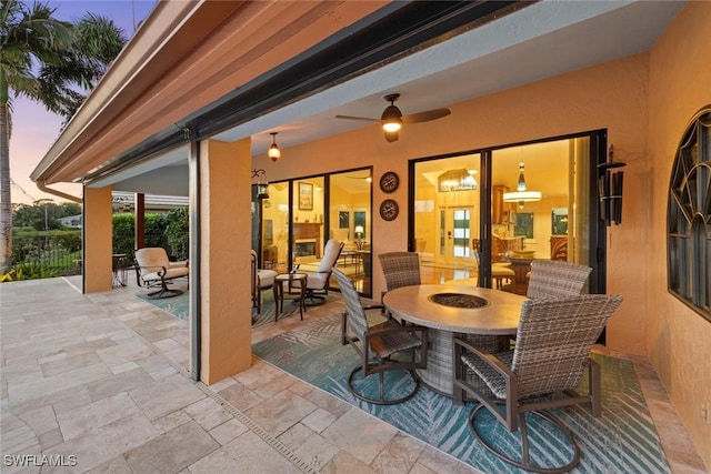 patio terrace at dusk featuring outdoor dining area and ceiling fan