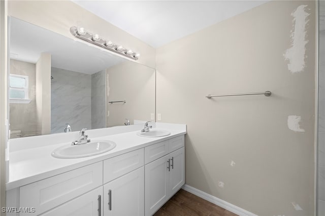 bathroom featuring double vanity, baseboards, and wood finished floors