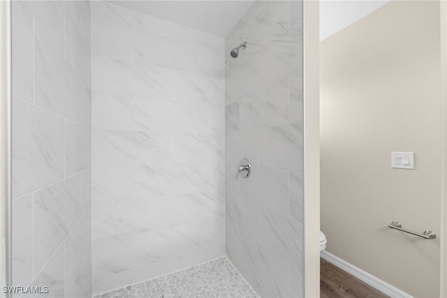 bathroom featuring tiled shower and toilet