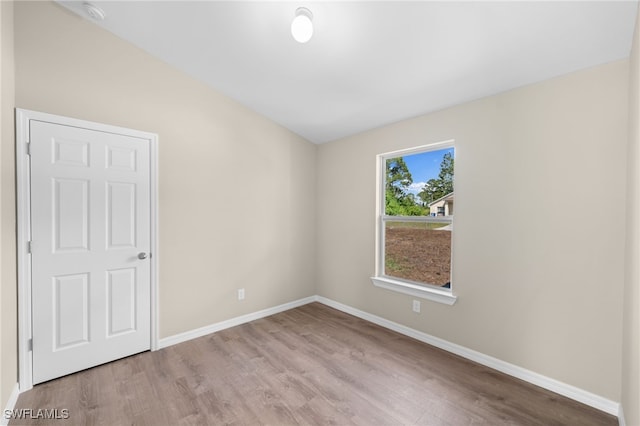unfurnished room featuring wood finished floors, baseboards, and a smoke detector