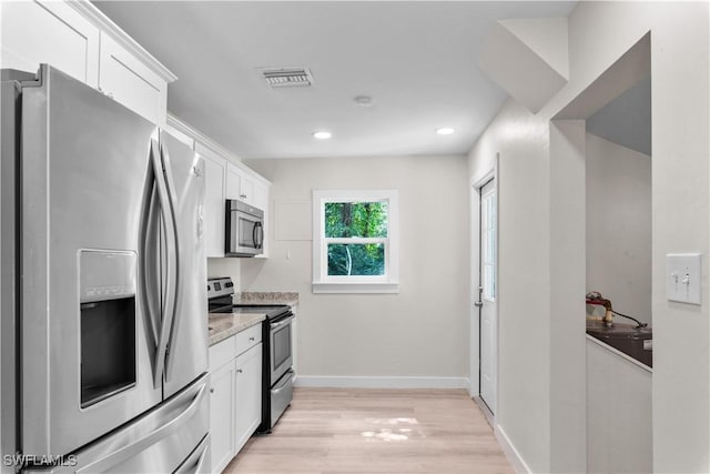 kitchen with appliances with stainless steel finishes, white cabinetry, light wood-type flooring, baseboards, and recessed lighting