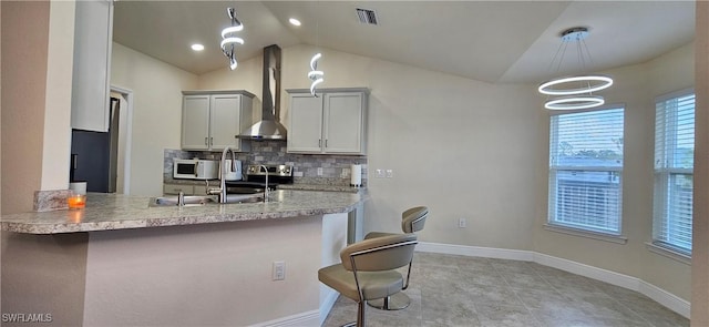 1948 Redmont Ave, Lehigh Acres, FL 33972 - kitchen featuring wall chimney range hood, white microwave, a breakfast bar, vaulted ceiling, and light countertops