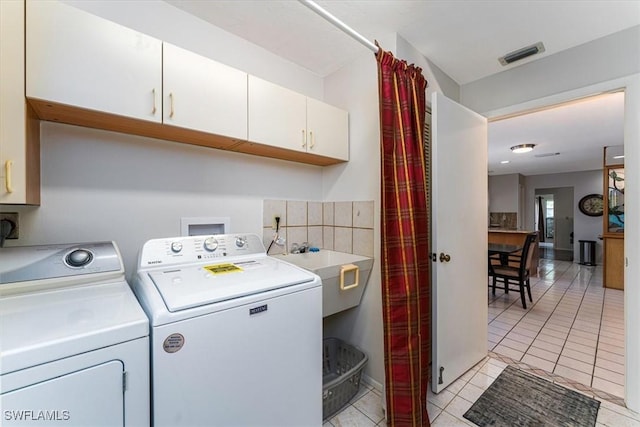 laundry room with washing machine and clothes dryer, cabinet space, and light tile patterned flooring