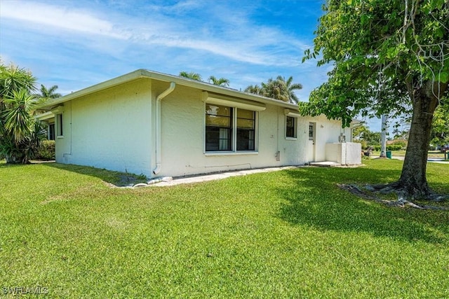 rear view of house with stucco siding and a yard