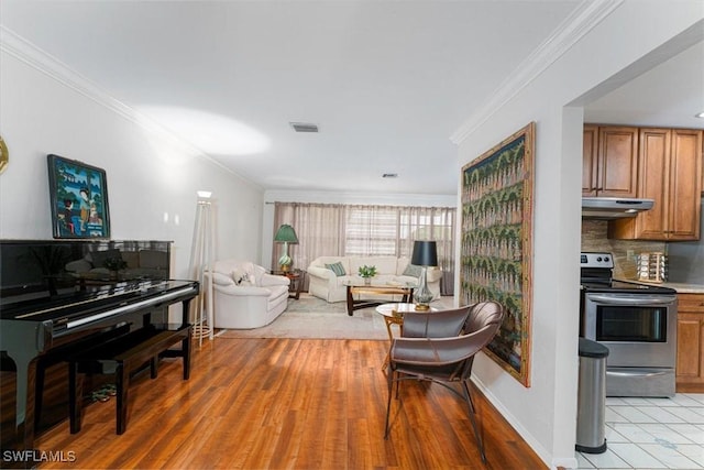 living area with ornamental molding, baseboards, and light wood-style floors
